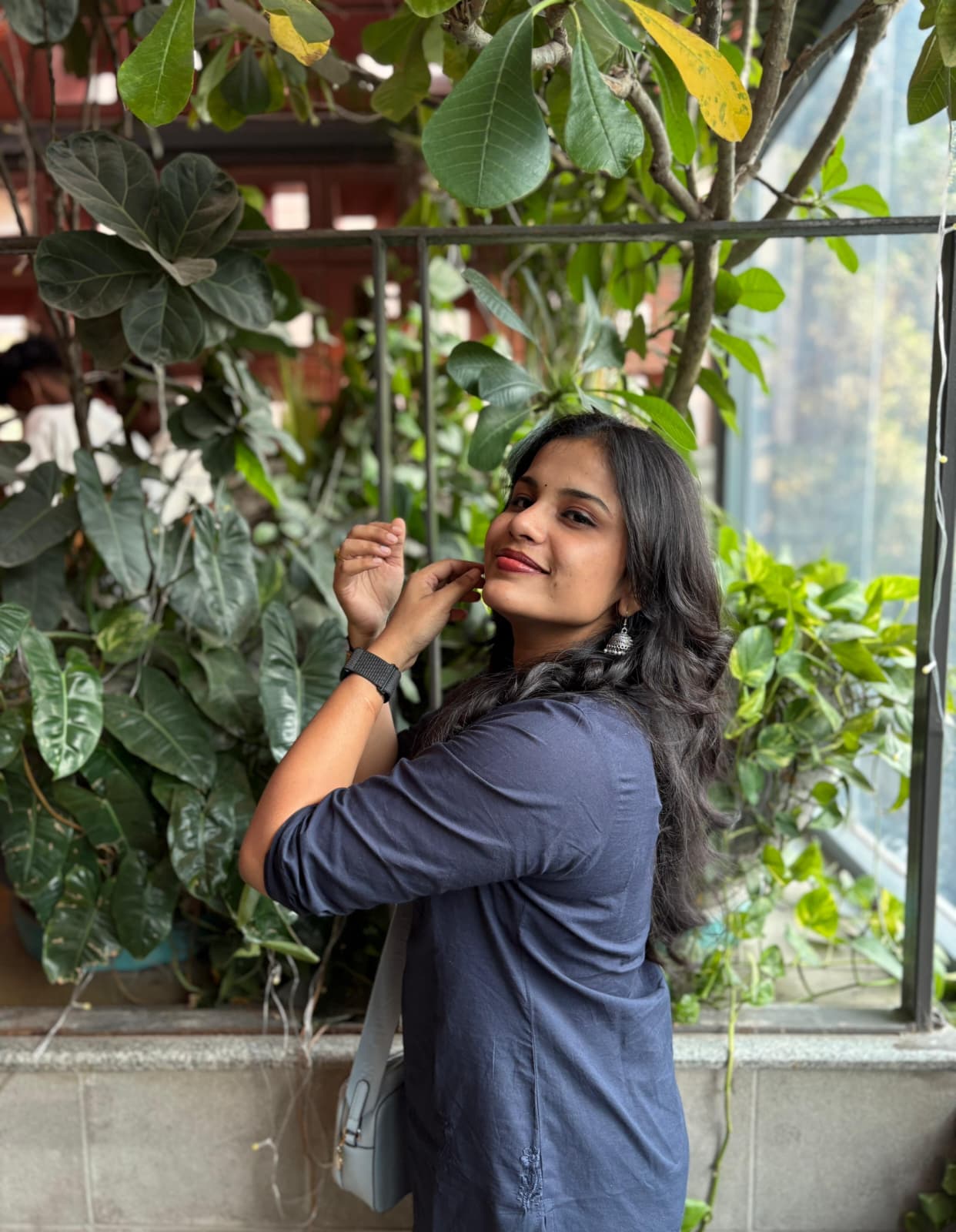 Supriya beside a leafy window